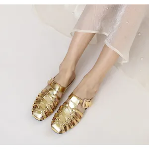 Detailed close-up of gold woven mule sandals with square metal buckle on white background