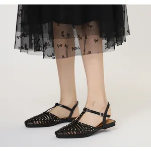 Details schwarzer spitze Sandalen mit Goldnieten und elegantem gewebtem Hohlraum-Design