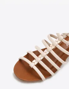 Detailopname van de PU-leren bandjes en gouden vlinderaccenten op de sandalen