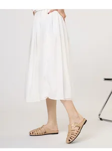 Detail of beige woven mules with gold buckle detail worn with a pleated skirt