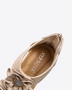 Detailed view of champagne wedge sandal featuring floral accents and padded insole