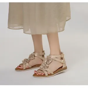 On-foot view of champagne gold flat sandals with bohemian flower details and ankle strap