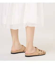 Detail view of beige woven mules with gold metal buckle and thin flat black soles