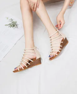 Bovenaanzicht van beige Romeinse sandalen met sleehak, bandjes en hak in houtstructuur