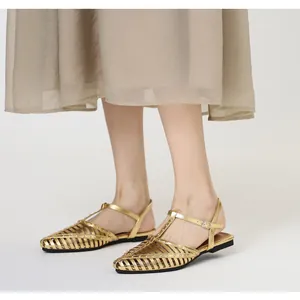 Detail von goldenen geflochtenen Sandalen mit T-Riemen und metallischem Hohl-Design