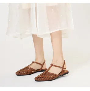 Detailansicht brauner hohl gewebter Sandalen mit Goldnieten und verstellbarem T-Riemen