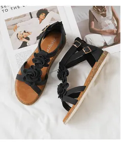 Detail of black gladiator sandals with 3D floral accents and non-slip wavy white soles