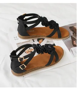 Detail view of black Roman sandals with floral accents and secure back zipper closure