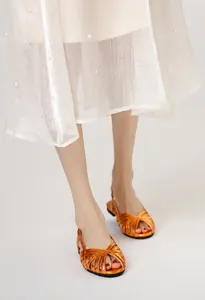 Detailansicht der Damen-Römersandalen in Metallic-Orange mit Kreuzgurten und Spitzenrock