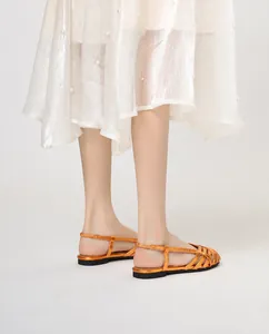 Nahaufnahme orangefarbener Metallic-Römersandalen kombiniert mit Perlenkleid