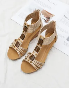 Detalle de sandalias de cuña con tira en T, hebilla de madera y tachuelas doradas