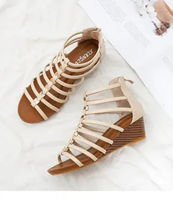 Detail van beige Romeinse sandalen met sleehak, gekruiste bandjes en metalen rits