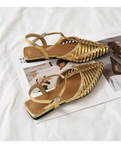 Detailansicht goldener spitzer Sandalen mit Nietenverzierung und T-Riemen