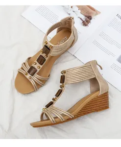 Detalle de sandalias de cuña color champán con tiras tejidas y adornos de madera oscura