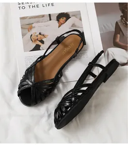 Detailaufnahme der schwarzen flachen Sandalen mit gekreuzten Riemen auf Modemagazin