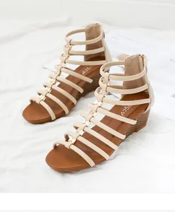 Detail van beige gladiator sleehak sandalen met gouden strikjes en rits aan de achterkant
