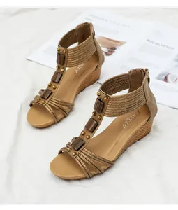 Detalle de sandalias de cuña con tiras cruzadas, remaches de metal y cremallera trasera