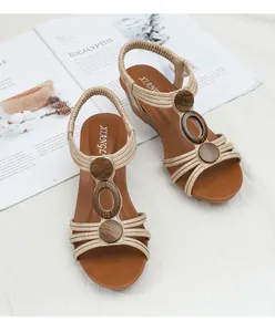 Detail of champagne gold wedge sandals with wood grain beads on a white surface