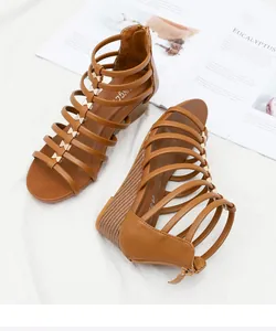 Detail van bruine romeinse sleehak sandalen met gouden strikjes en rits achteraan