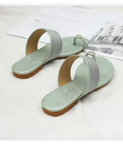 Détail de sandales plates vert menthe en daim avec boucle en strass et anneau d'orteil