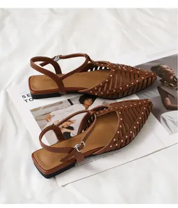 Detail brauner, spitzer Sandalen mit hohlen Streifen, Nieten und verstellbarem Riemen