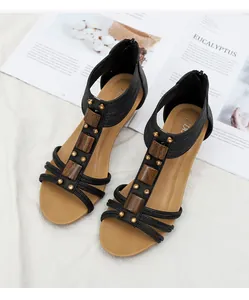 Detalle de sandalias negras con cuña, bloques de madera y remaches dorados