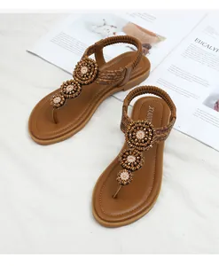 Detail of bohemian T-strap flat sandals featuring three intricate beaded flowers and elastic strap