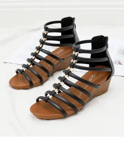 Detail van sleehak sandalen met gouden vlindergesp en een rits aan de achterkant