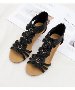 Detail of black wedge sandals featuring three 3D flowers with gold metal centers