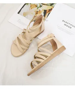 Close-up of beige bohemian roman sandals with braided straps and metal buckles