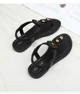 Close-up of beaded black floral sandals with elegant gold accents and elastic back strap