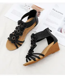 Detailed view of bohemian wedge sandals with three 3D black flowers and wood-grain heels
