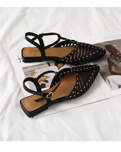 Details von schwarzen Leder-Sandalen mit Ausschnitten, Goldnieten und Knöchelriemen