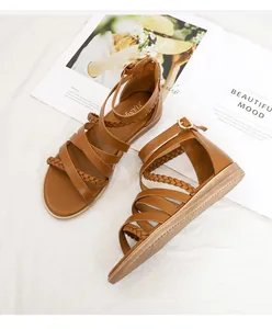 Detail of brown Roman braided sandals featuring multiple straps and metal buckle on white fabric