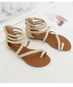 Détail de sandales compensées beiges avec brides tressées et fermeture éclair arrière