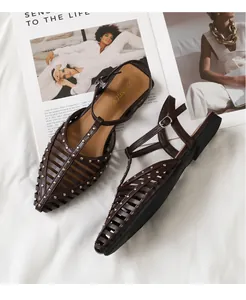 Detailaufnahme brauner Käfigsandaletten mit Goldnieten auf Modemagazin