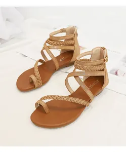 Détail de sandales gladiateur marron avec lanières tressées et boucle métallique
