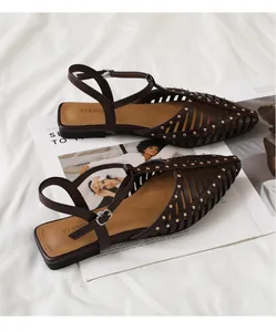 Detail der dunkelbraunen spitzen Hohlsandalen mit goldenen Nieten auf Modemagazin