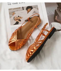 Draufsicht auf metallisch orangefarbene Sandalen mit geflochtenen Riemen auf Modemagazin