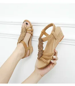 Detail of bohemian wedge sandals featuring metallic feather charms and cork texture soles