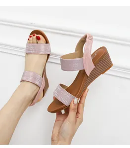 Detail of pink glitter wedge sandals with textured brown sole and elastic heel strap