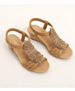 Detail of bohemian wedge sandal featuring a decorative feather ornament and elastic back strap