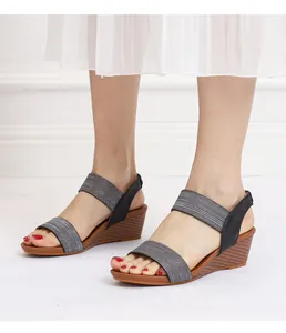 Side view of women's wedge sandals with grey elastic straps and textured brown heel