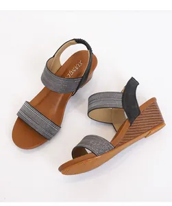 Detail view of grey glitter fabric and elastic heel strap on women's wedge sandals
