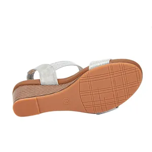 Detail view of the non-slip rubber sole and wood-textured wedge heel on silver sandals