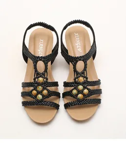 Vista superior de sandalias bohemias con cuña, tiras trenzadas negras y cuentas amarillas