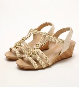 Detalle de sandalias de cuña bohemias con correas trenzadas, cuentas y suela efecto madera