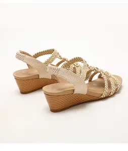 Detalle de sandalias de cuña bohemias con tiras trenzadas y correa elástica en el talón