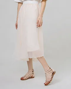Detail of beige gladiator sandals paired with a pleated light pink chiffon maxi skirt