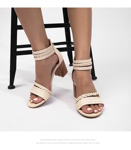 Detalle de sandalias beige con tacón de bloque trenzado y correas al tobillo puestas en modelo